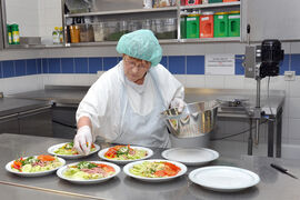 Gesund und frisch: Eine Mitarbeiterin der Zentralküche des UKJ richtet Salate an. (Foto: UKJ/Schacke)