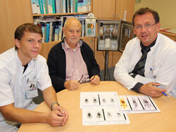 UKJ-Nuklearmediziner Dr. Thomas Winkens (links) und PD Dr. Martin Freesmeyer (rechts), Chefarzt der Klinik für Nuklearmedizin am UKJ, erläutern dem ersten Patienten die Wirkungsweise der neuartigen PSMA-Therapie bei Prostatakrebs. Foto: UKJ. 